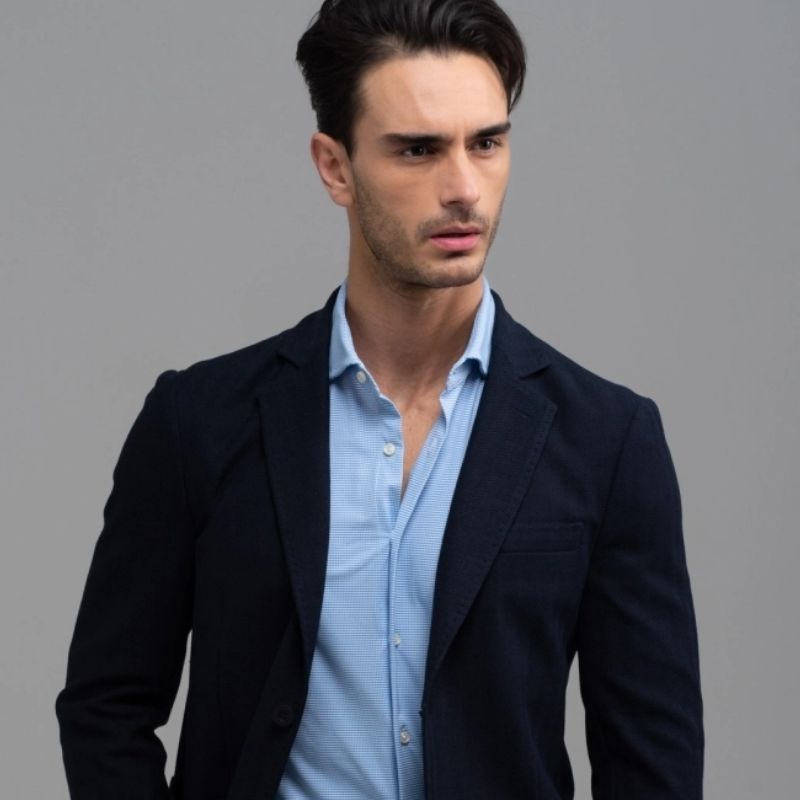 Ragazzo con giacca blu in tessuto spigato e camicia azzurra